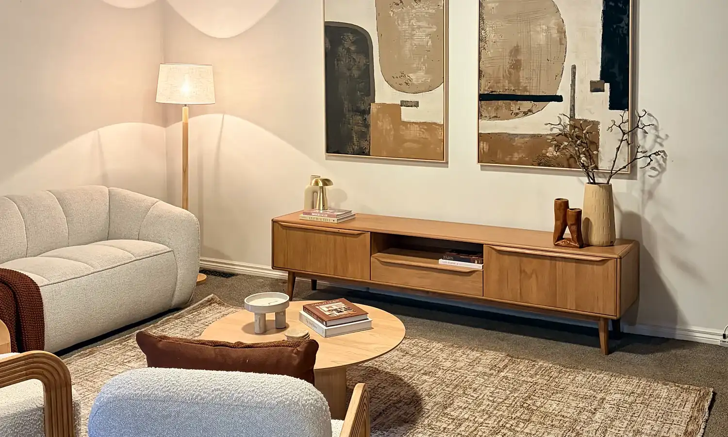 Living room with a timber-lined ceiling, cream sofa, boucle armchairs and round coffee table.