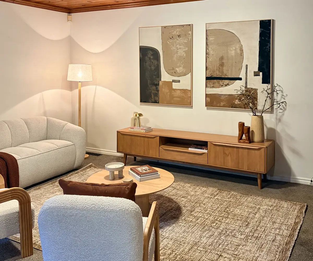 Living room with a timber-lined ceiling, cream sofa, boucle armchairs and round coffee table.