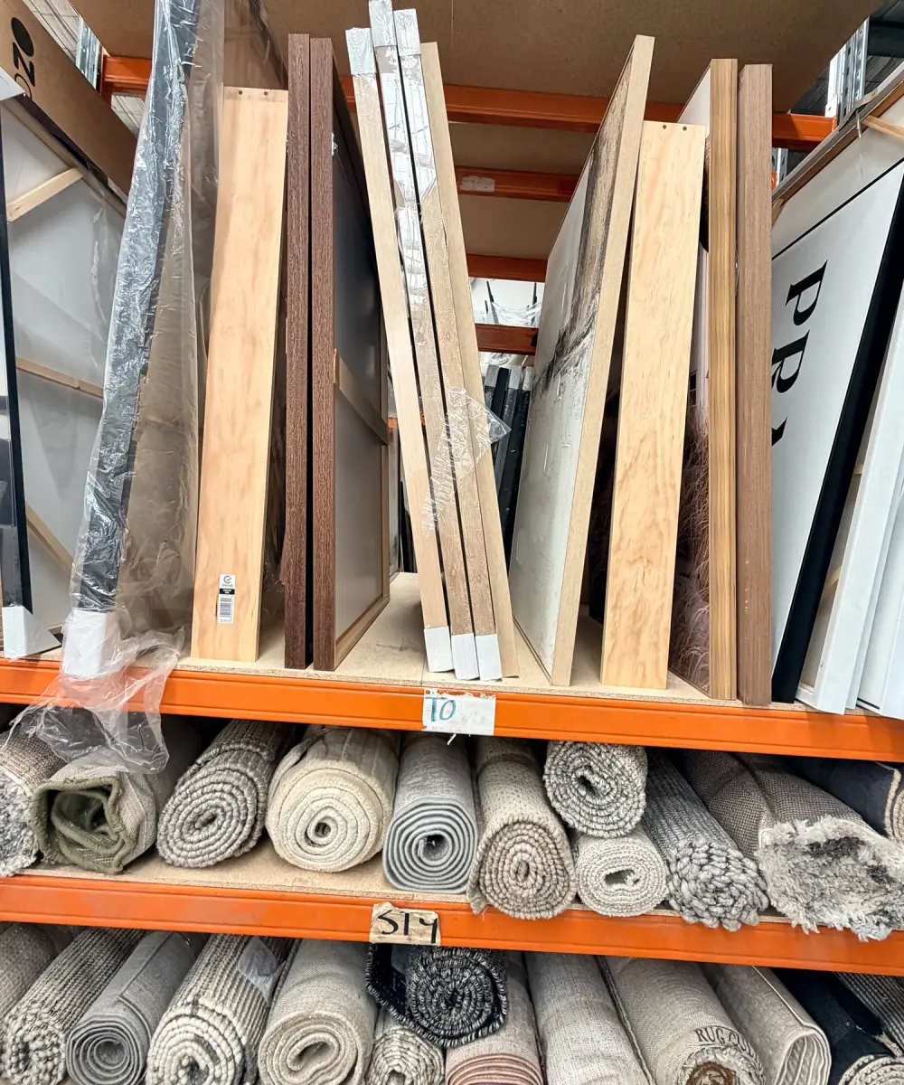 Framed artwork and rolled rugs on racking in the Staged Right Co factory.