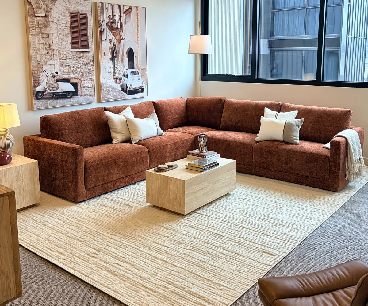 Living room with a rust modular sofa, cream rug and travertine coffee table.