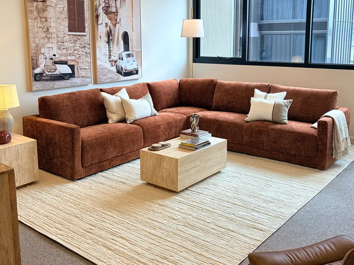 Living room with a rust modular sofa, cream rug and travertine coffee table.