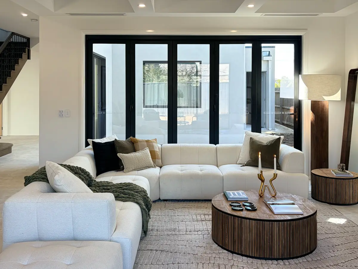 Open living area with a cream modular sofa, round fluted timber coffee table and coffered ceiling.