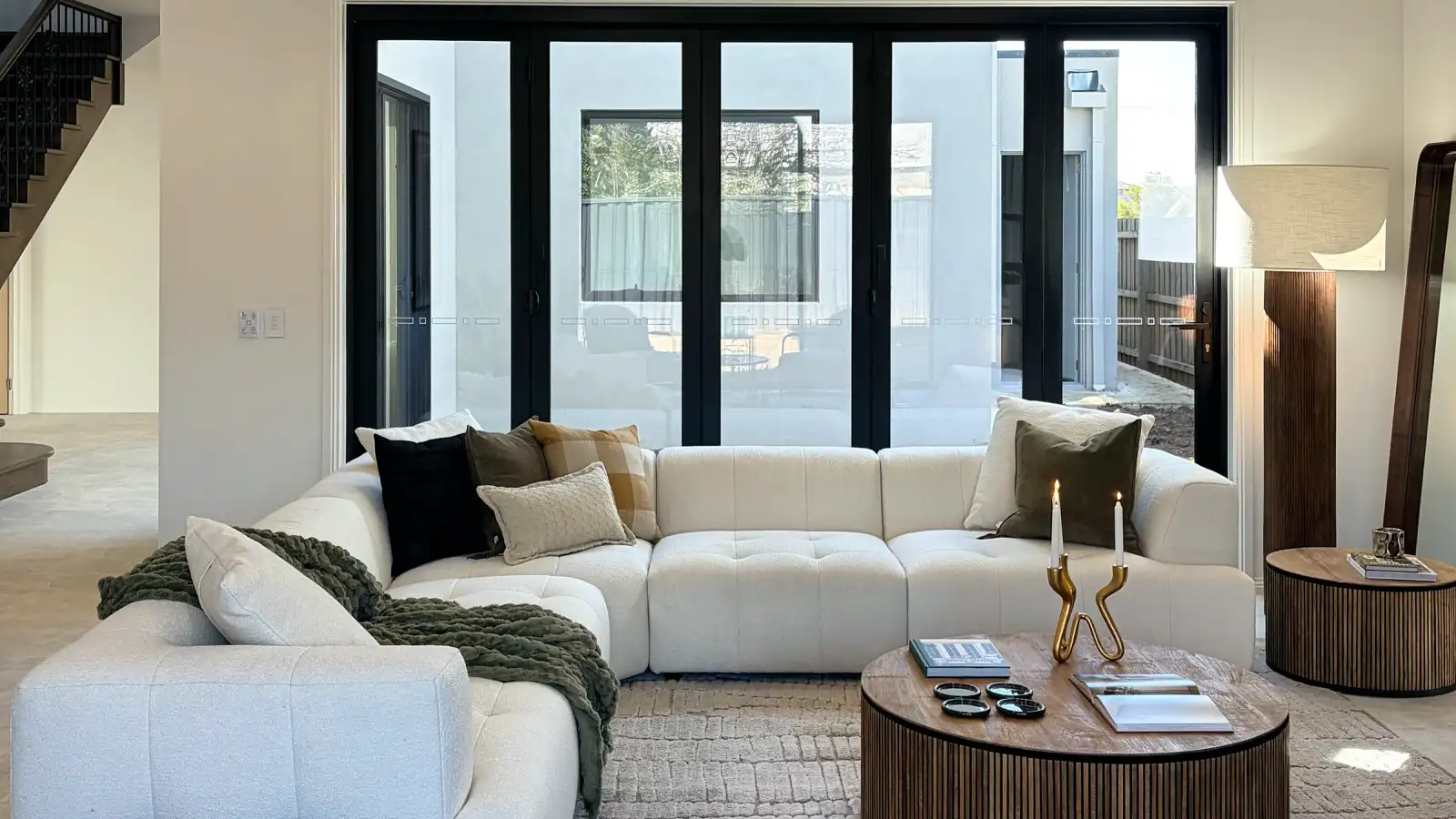 Open living area with a cream modular sofa, round fluted timber coffee table and coffered ceiling.