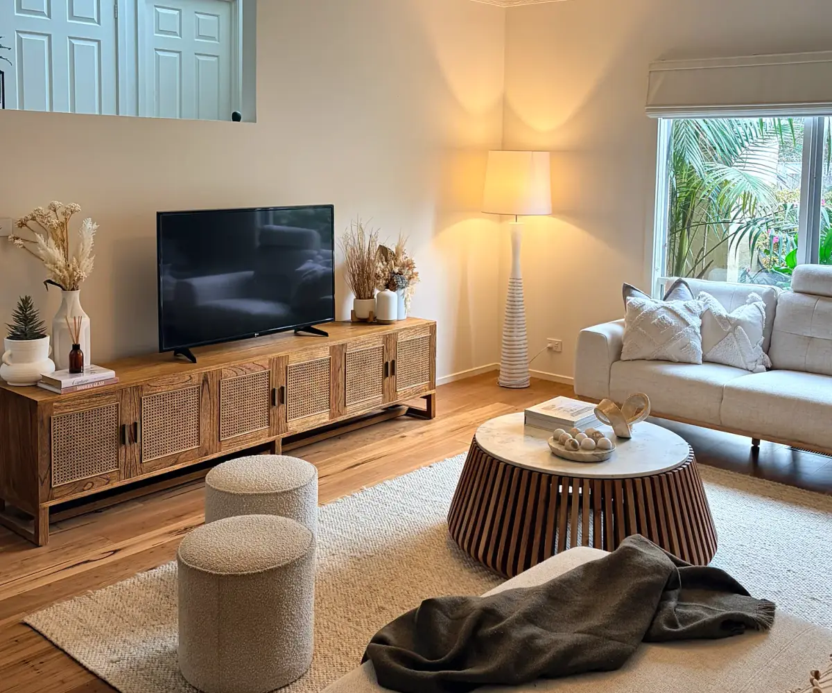 Living room with a timber TV unit, cream sofas and a marble-topped coffee table.