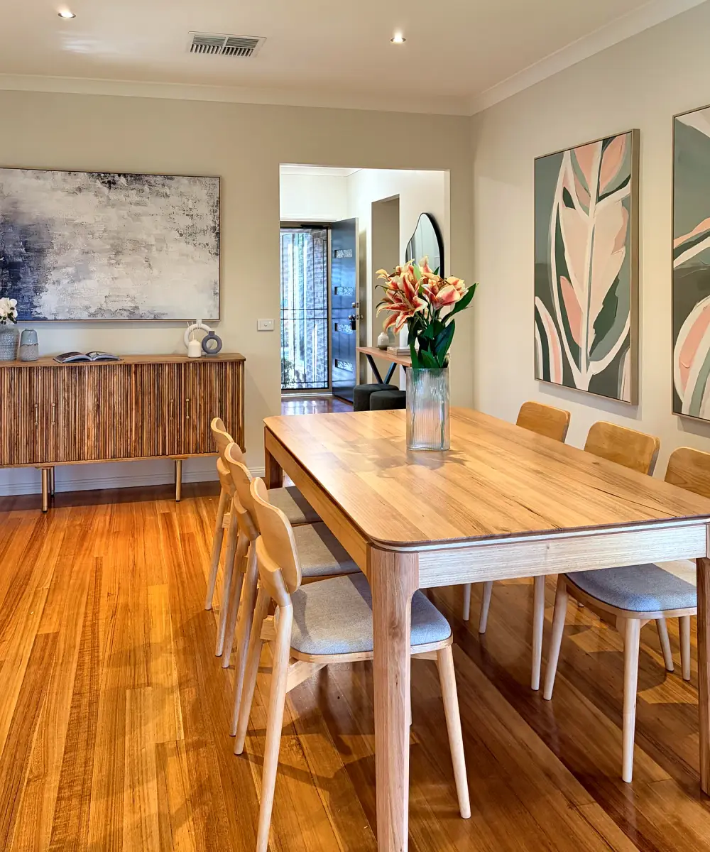 Dining area with a timber table and chairs, fluted sideboard and botanical artwork.