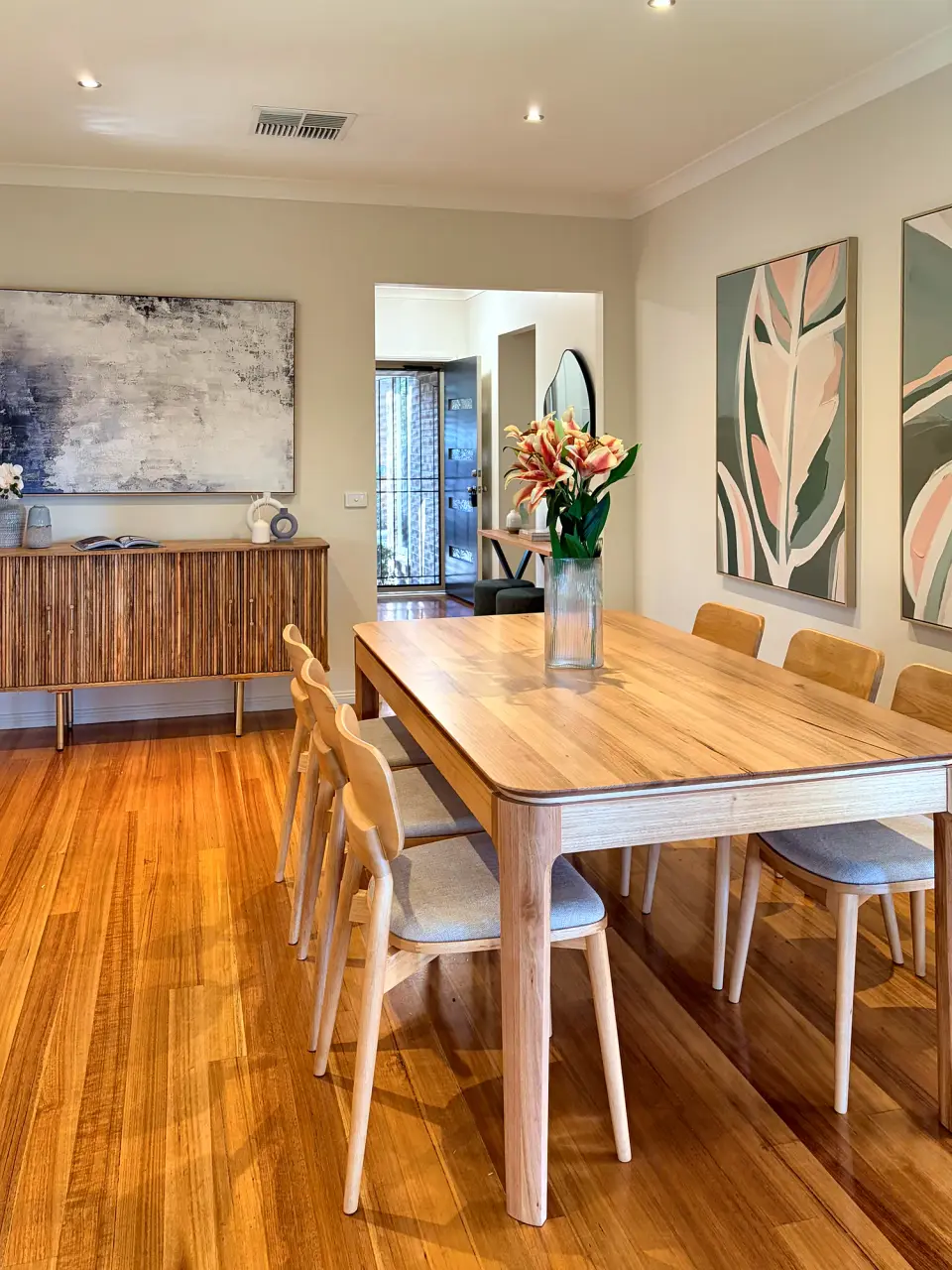 Dining area with a timber table and chairs, fluted sideboard and botanical artwork.