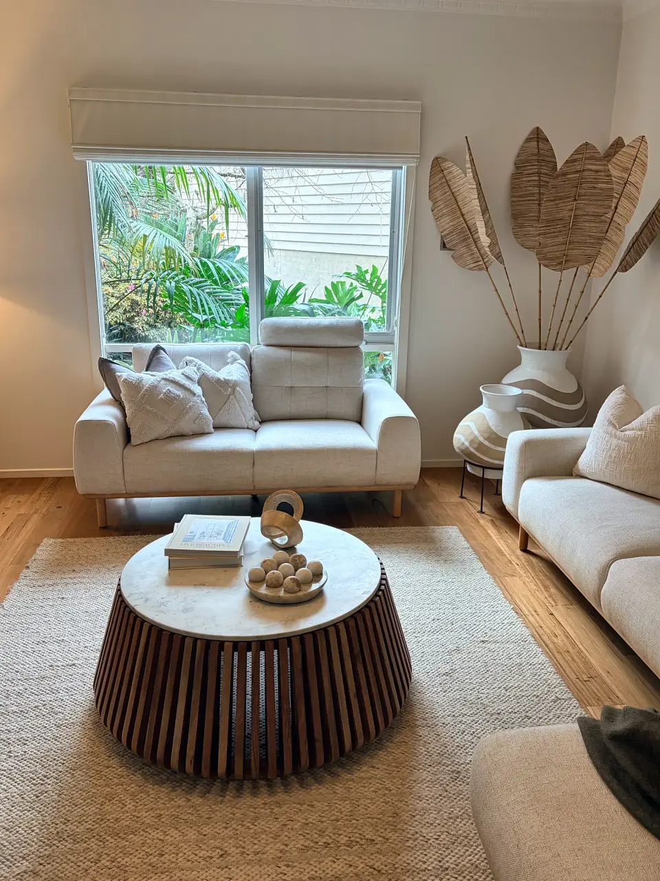Cream sofa and armchair around a round coffee table beside the window.
