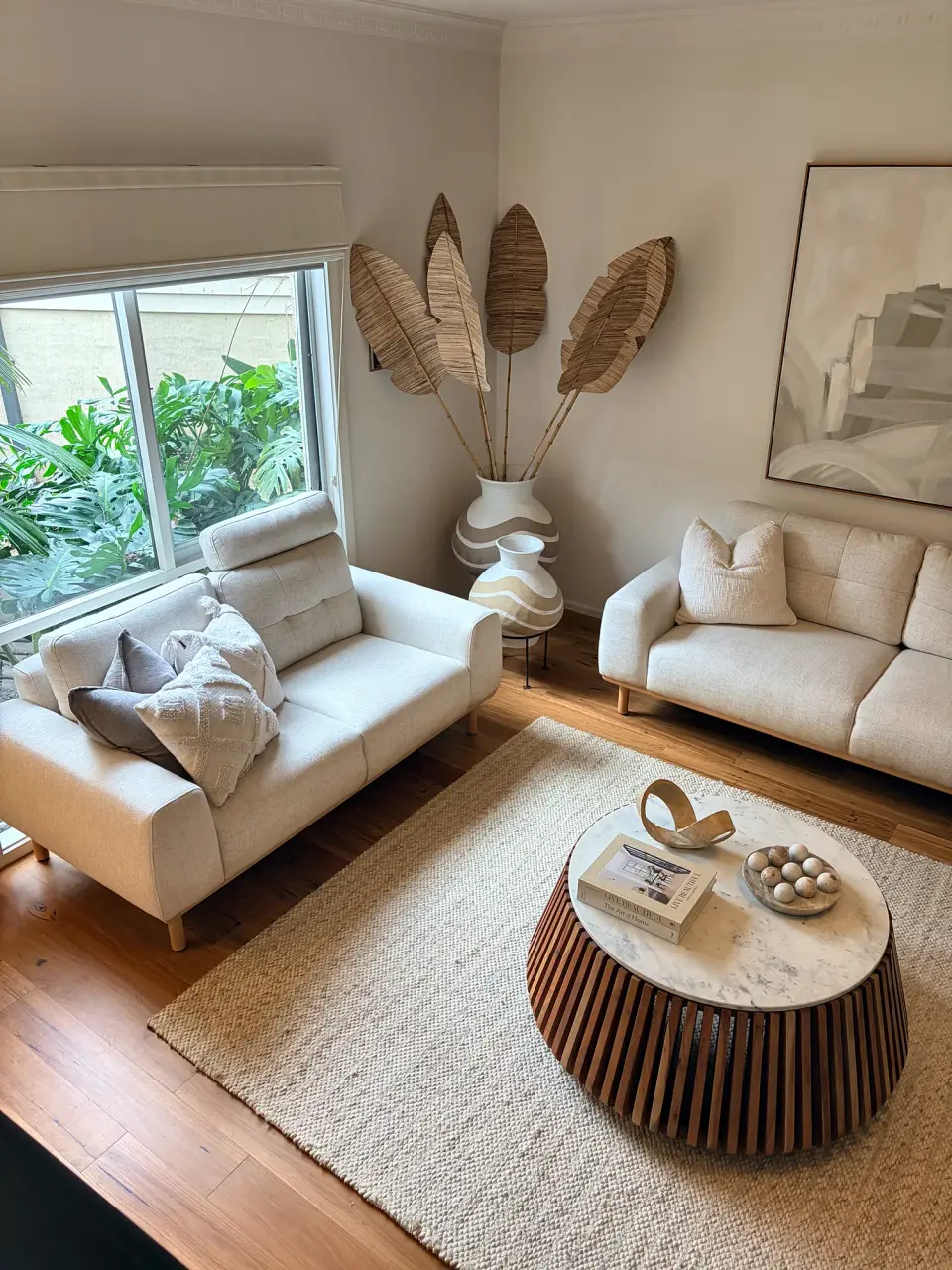 Cream sofa by the window with a marble-topped fluted coffee table.