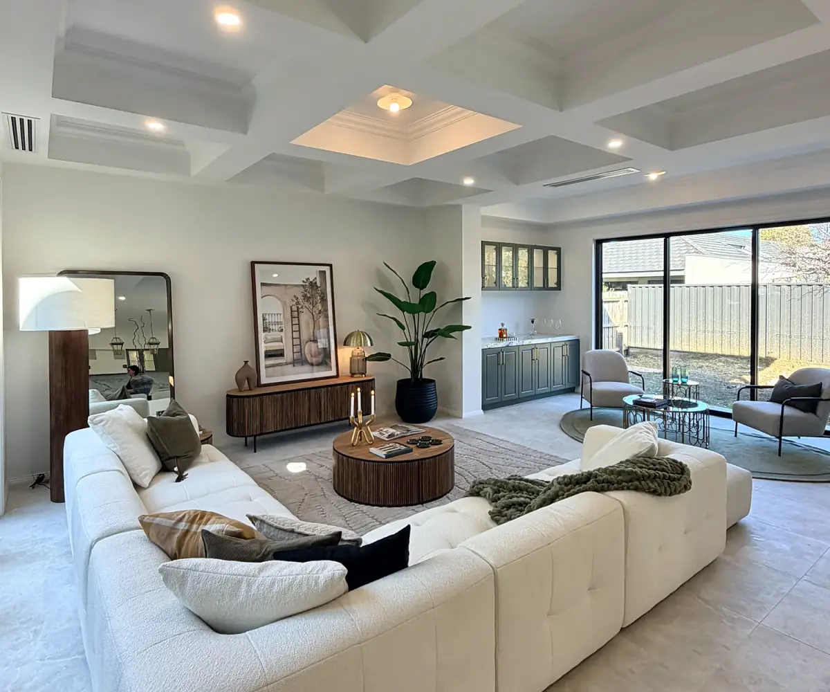 Wide view of the living area with a cream modular sofa under a coffered ceiling.