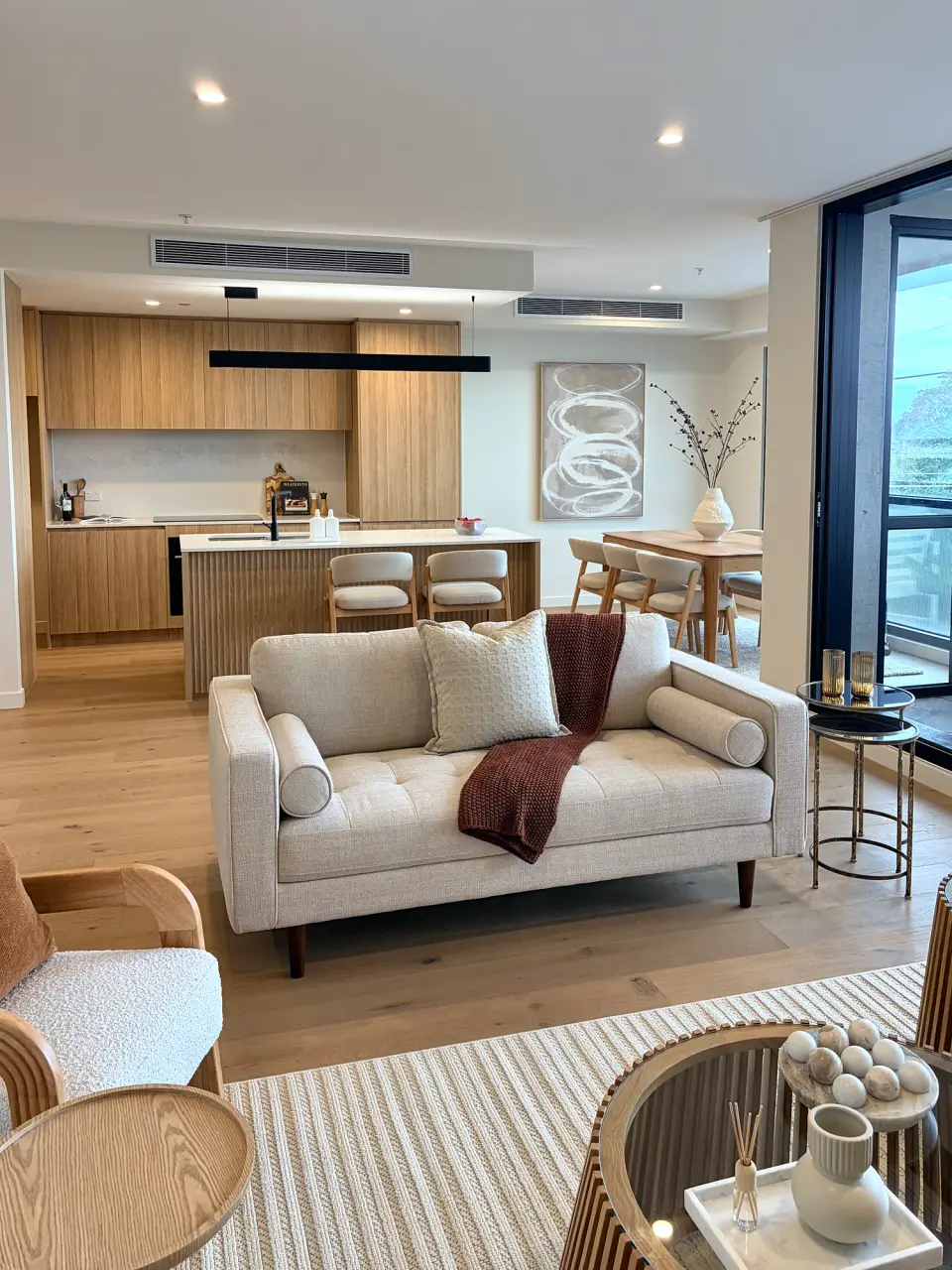 Second living area with a cream sofa and curved armchairs, open to the kitchen.