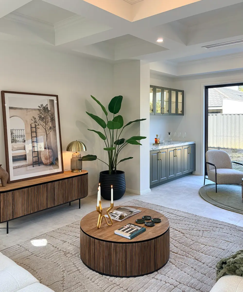 Fluted timber sideboard, framed artwork, large plant and round coffee table in the living area.