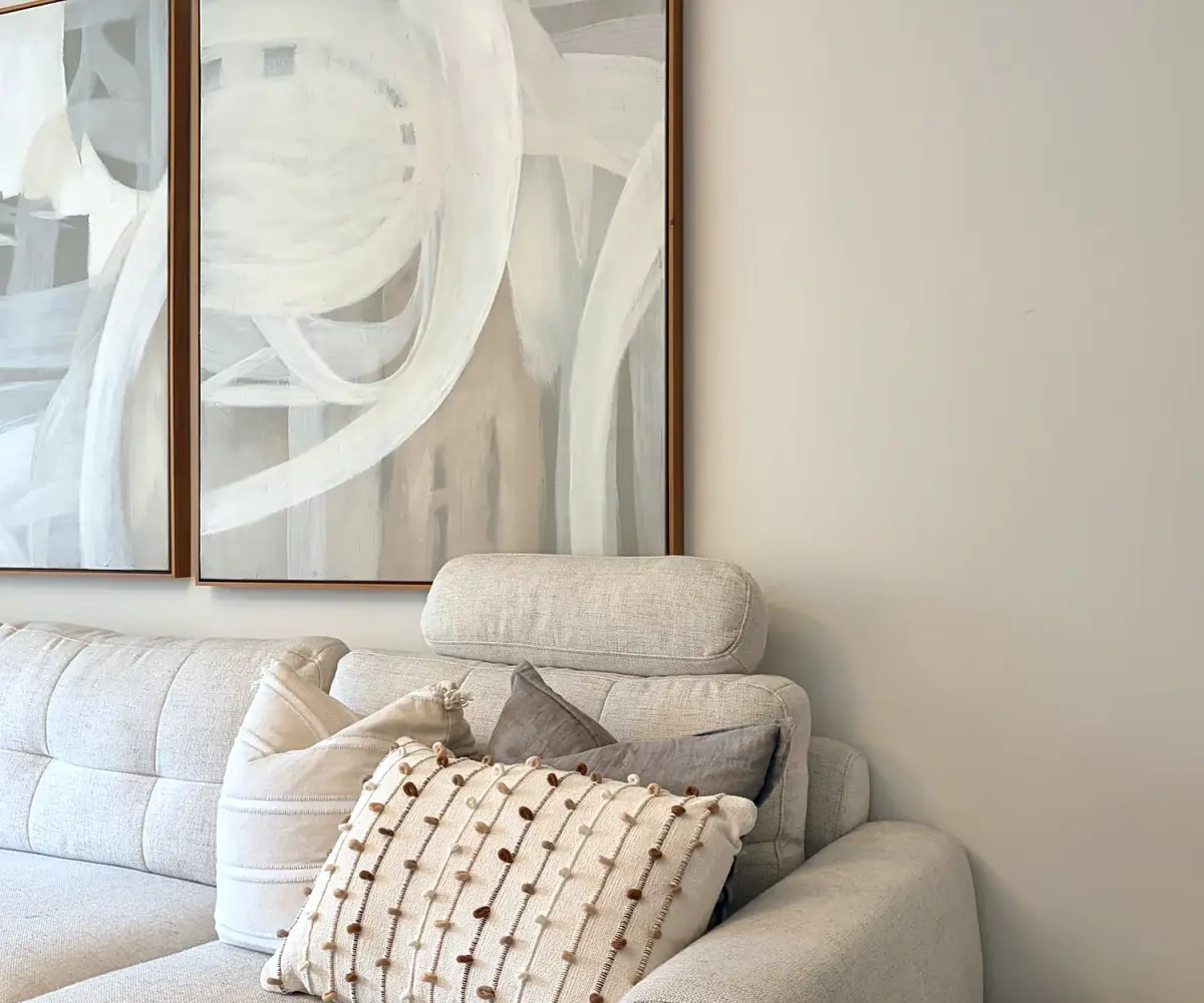 Cream sofa with textured cushions below a pair of abstract artworks.