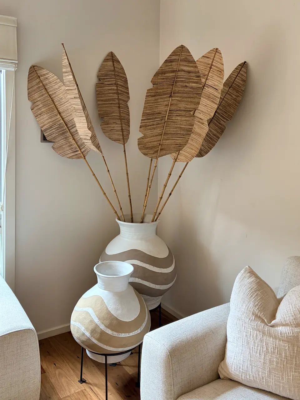 Patterned white vases with dried palm leaves in the corner of the living room.