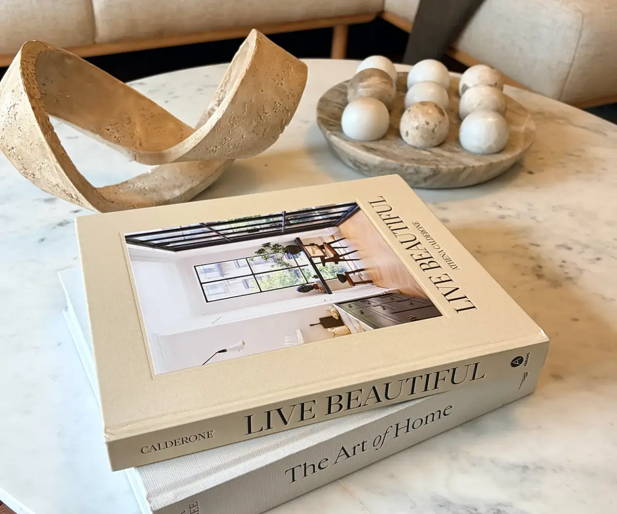 Marble coffee table styled with design books, a stone bowl and a sculpture.