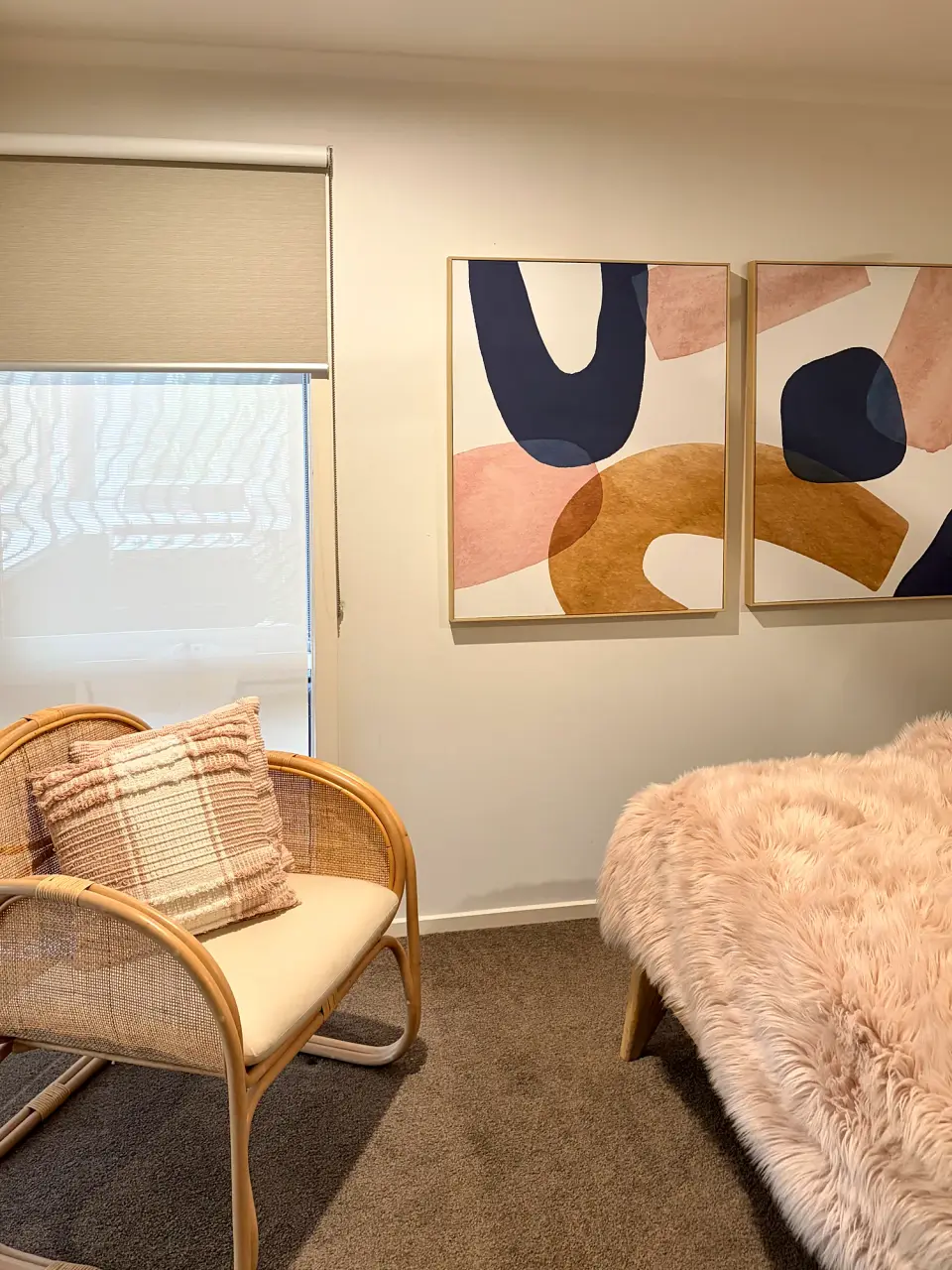 Bedroom corner with a rattan armchair and abstract artwork.