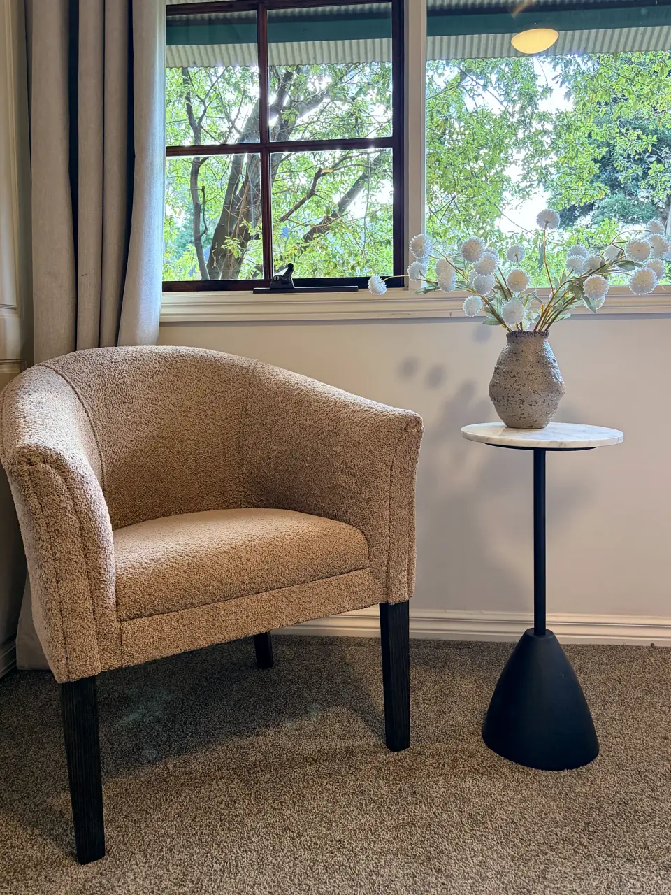 Tub armchair and black side table beside a window.